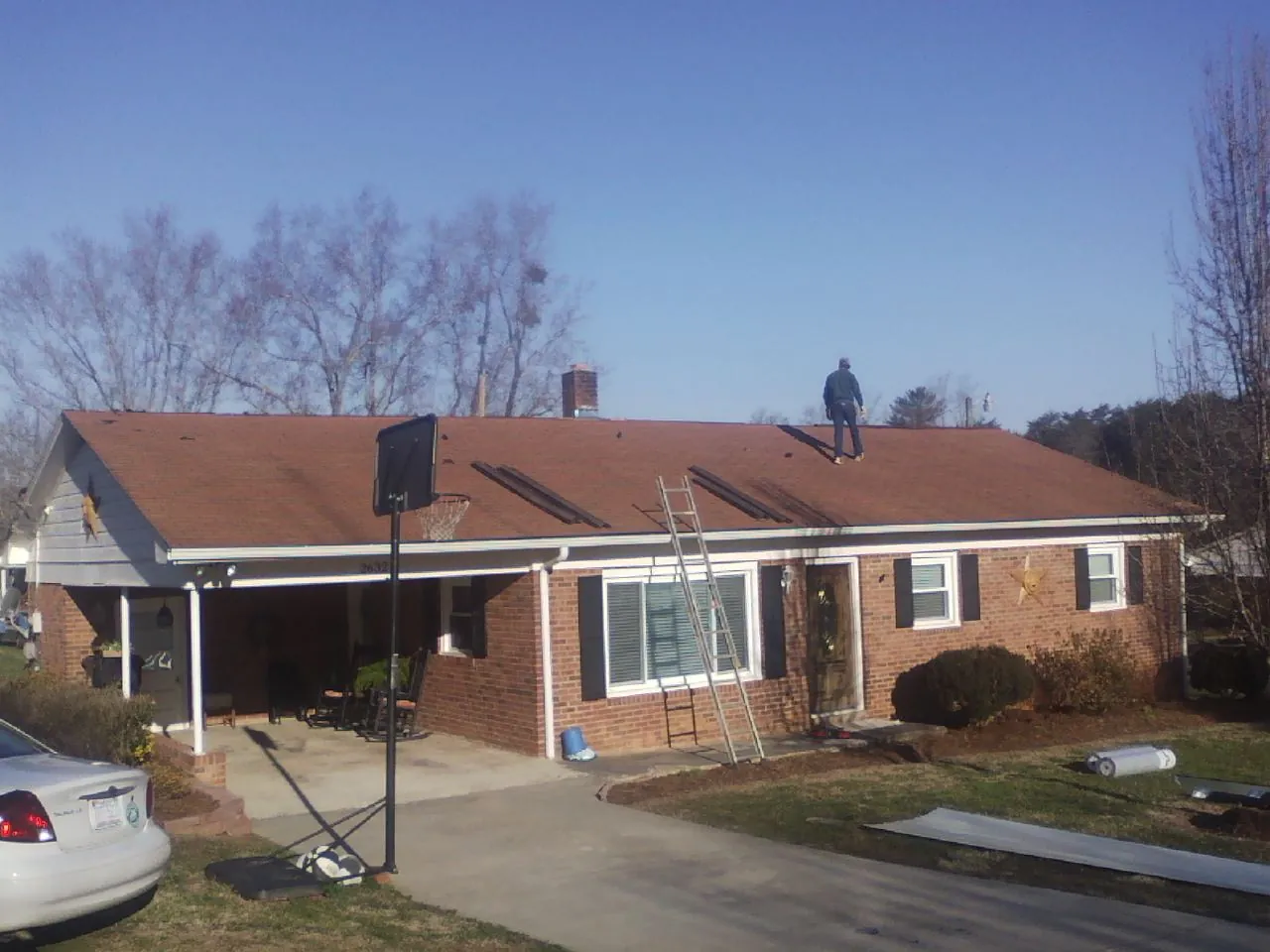 Roofer stripping a shingle roof on a brick ranch before metal panels in Montrose