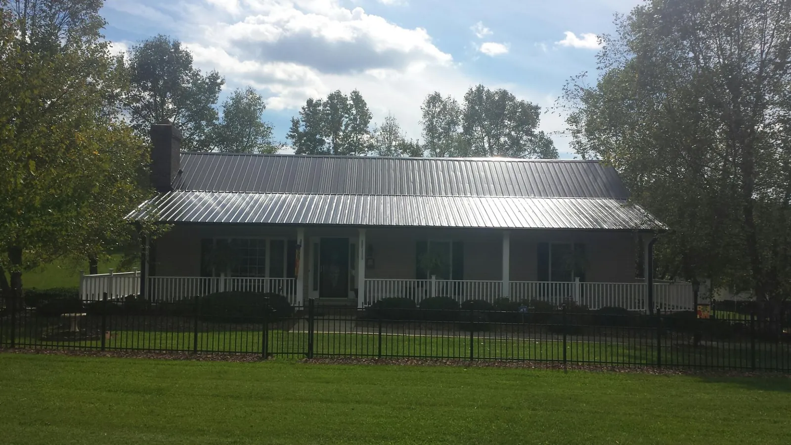 Gray metal roof on a brick ranch with a full width front porch — Gutter Guard Installation work by our crew in Montrose